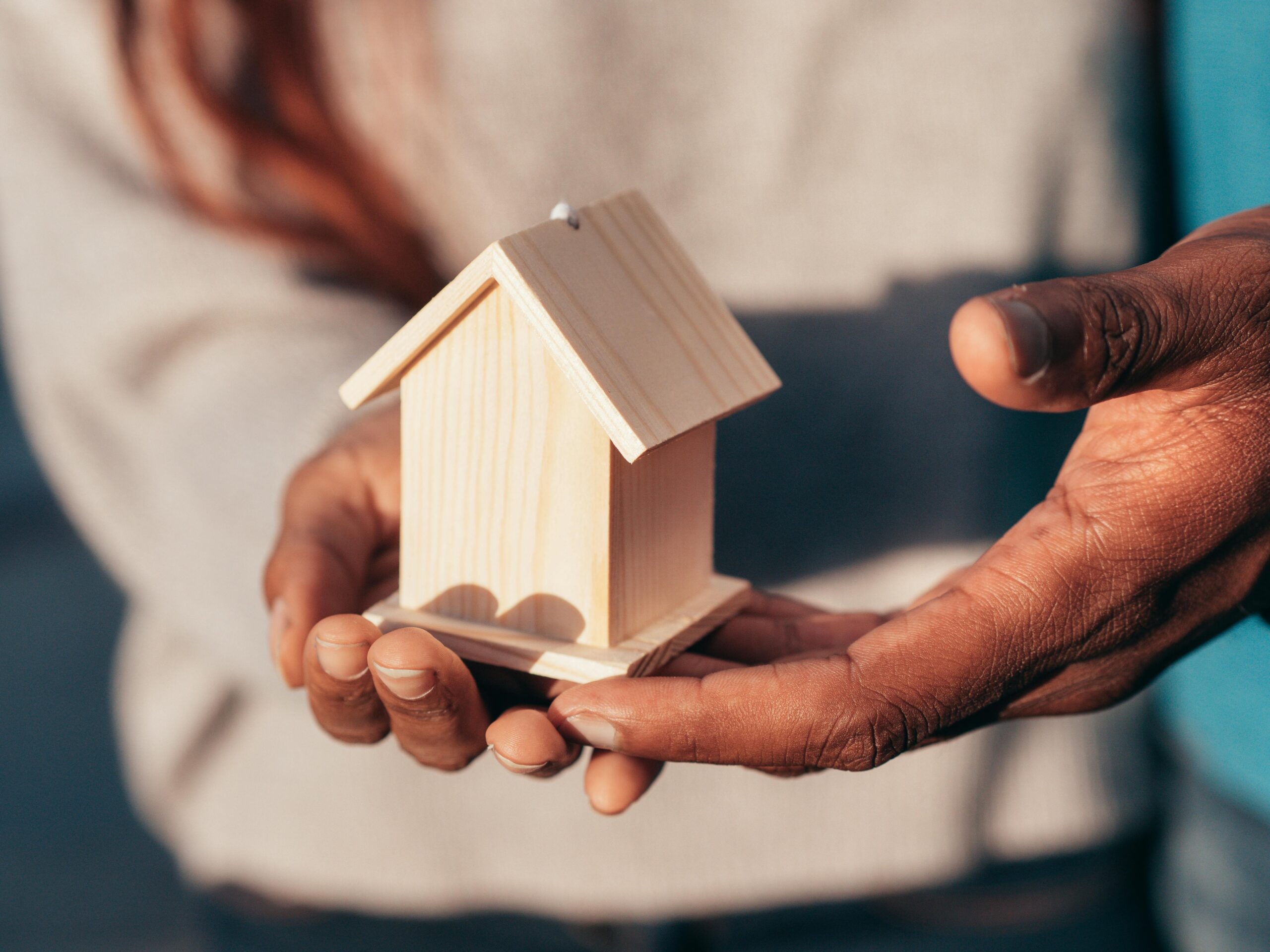Hands holding a small wooden house