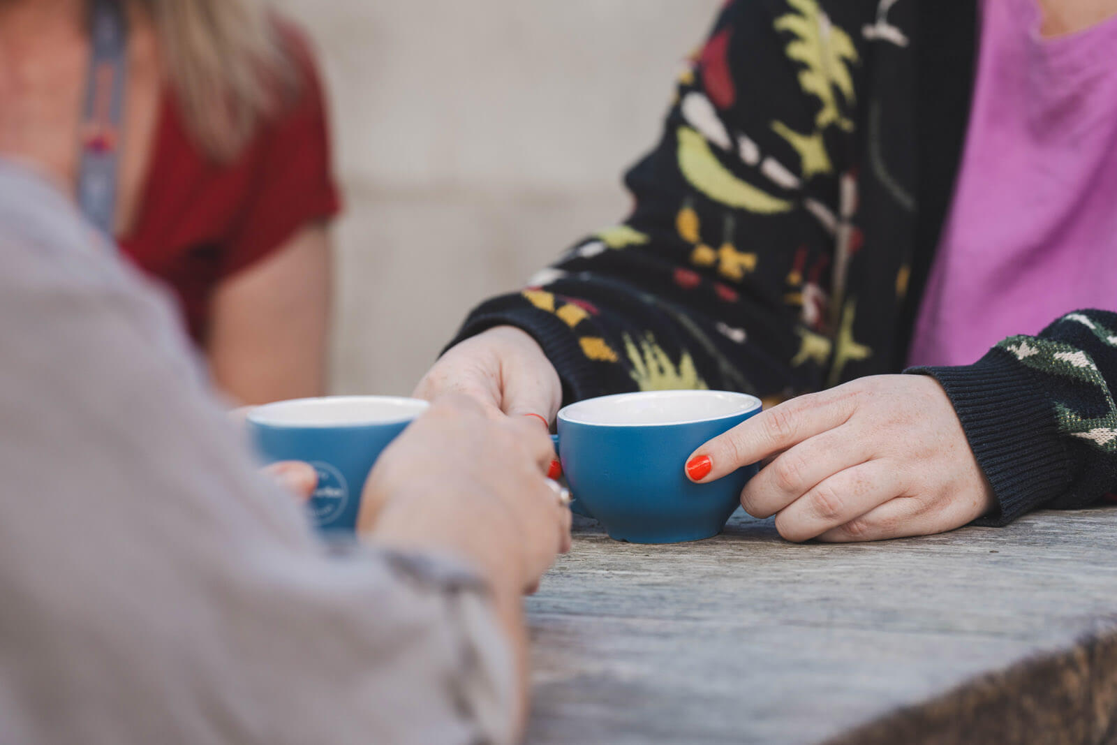Three people at a table, showing their hands and coffee cups