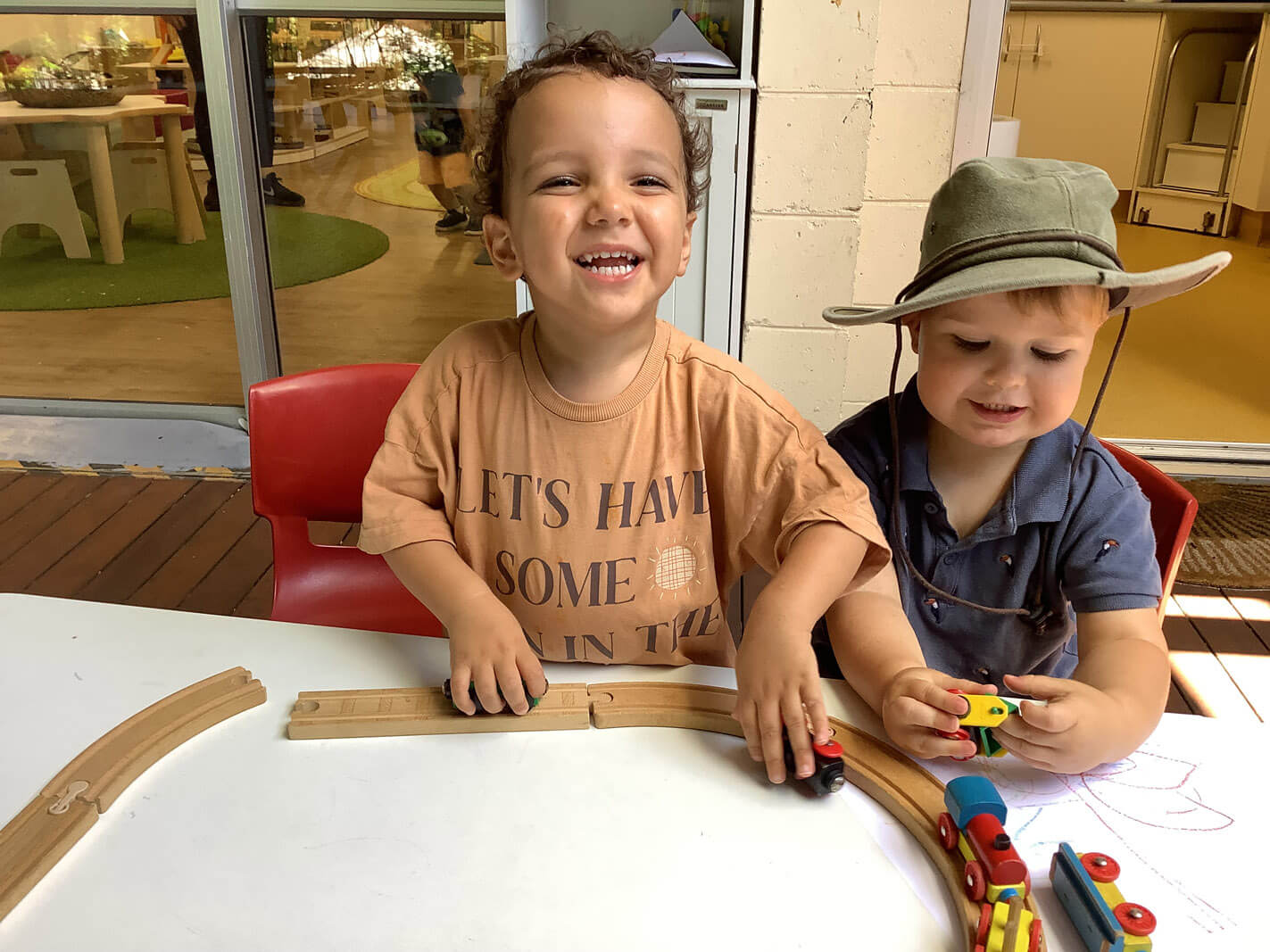 Two children smiling and laughing while playing with toy train